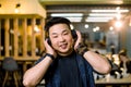 Young Chinese man in a modern office listening to something through ear head phones by putting hand on the ears Royalty Free Stock Photo