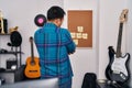 Young chinese man musician standing looking reminder corkboard at music studio