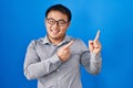 Young chinese man standing over blue background smiling and looking at the camera pointing with two hands and fingers to the side Royalty Free Stock Photo