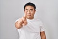 Young chinese man standing over white background pointing with finger up and angry expression, showing no gesture Royalty Free Stock Photo