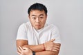 Young chinese man standing over white background shaking and freezing for winter cold with sad and shock expression on face Royalty Free Stock Photo