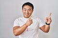Young chinese man standing over white background smiling and looking at the camera pointing with two hands and fingers to the side Royalty Free Stock Photo