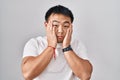 Young chinese man standing over white background tired hands covering face, depression and sadness, upset and irritated for Royalty Free Stock Photo