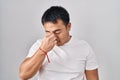 Young chinese man standing over white background tired rubbing nose and eyes feeling fatigue and headache Royalty Free Stock Photo