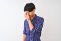 Young chinese man wearing casual blue shirt standing over isolated white background tired rubbing nose and eyes feeling fatigue Royalty Free Stock Photo