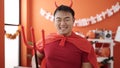 Young chinese man wearing devil costume holding trident at home