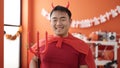Young chinese man wearing devil costume holding trident at home