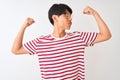 Young chinese man wearing glasses and striped t-shirt standing over isolated white background showing arms muscles smiling proud Royalty Free Stock Photo