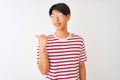 Young chinese man wearing glasses and striped t-shirt standing over isolated white background smiling with happy face looking and Royalty Free Stock Photo