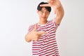 Young chinese man wearing glasses and striped t-shirt standing over isolated white background smiling making frame with hands and Royalty Free Stock Photo