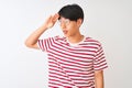 Young chinese man wearing glasses and striped t-shirt standing over isolated white background very happy and smiling looking far Royalty Free Stock Photo