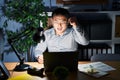 Young chinese man working using computer laptop at night angry and mad raising fist frustrated and furious while shouting with Royalty Free Stock Photo