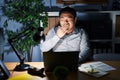 Young chinese man working using computer laptop at night bored yawning tired covering mouth with hand Royalty Free Stock Photo