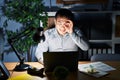 Young chinese man working using computer laptop at night doing ok gesture with hand smiling, eye looking through fingers with Royalty Free Stock Photo