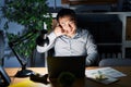 Young chinese man working using computer laptop at night smiling doing phone gesture with hand and fingers like talking on the Royalty Free Stock Photo