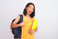 Young chinese student woman wearing backpack holding book over isolated white background very happy pointing with hand and finger Royalty Free Stock Photo