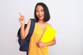 Young chinese student woman wearing backpack holding book over isolated white background very happy pointing with hand and finger Royalty Free Stock Photo