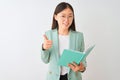 Young chinese student woman wearing glasses reading book over isolated white background happy with big smile doing ok sign, thumb Royalty Free Stock Photo