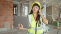 Young chinese woman architect using laptop talking on smartphone at construction site Royalty Free Stock Photo