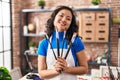 Young chinese woman artist smiling confident holding paintbrushes at art studio