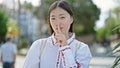 Young chinese woman doing silent gesture at park