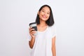 Young chinese woman drinking take away glass of coffee over isolated white background with a happy face standing and smiling with Royalty Free Stock Photo