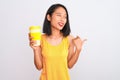 Young chinese woman drinking take away glass of coffee over isolated white background pointing and showing with thumb up to the Royalty Free Stock Photo