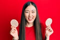 Young chinese woman eating healthy rice crackers smiling and laughing hard out loud because funny crazy joke