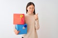 Young chinese woman holding birthday gifts over isolated white background doing happy thumbs up gesture with hand