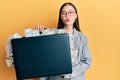 Young chinese woman holding briefcase full of dollars looking at the camera blowing a kiss being lovely and sexy