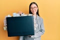 Young chinese woman holding briefcase full of dollars smiling with a happy and cool smile on face Royalty Free Stock Photo