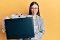 Young chinese woman holding briefcase full of dollars sticking tongue out happy with funny expression Royalty Free Stock Photo