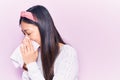 Young chinese woman illness wearing diadem using paper handkerchief on nose