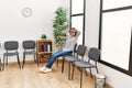 Young chinese woman listening to music sitting on chair at waiting room Royalty Free Stock Photo