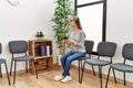 Young chinese woman listening to music sitting on chair at waiting room Royalty Free Stock Photo