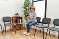 Young chinese woman listening to music sitting on chair at waiting room Royalty Free Stock Photo