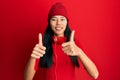 Young chinese woman listening to music using headphones approving doing positive gesture with hand, thumbs up smiling and happy Royalty Free Stock Photo