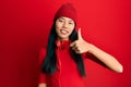 Young chinese woman listening to music using headphones doing happy thumbs up gesture with hand Royalty Free Stock Photo