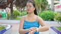 Young chinese woman looking watch with serious expression at park Royalty Free Stock Photo