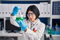 Young chinese woman scientist holding measuring liquid at laboratory Royalty Free Stock Photo