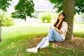 Young Chinese woman sitting sleeping in shadow under green tree on sunny day Royalty Free Stock Photo