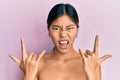 Young chinese woman standing topless showing skin shouting with crazy expression doing rock symbol with hands up Royalty Free Stock Photo