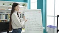 Young chinese woman student smiling confident explaining maths exercise at library university