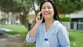 Young chinese woman talking on the smartphone holding bottle of water at park Royalty Free Stock Photo