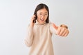 Young chinese woman talking on the smartphone over isolated white background approving doing positive gesture with hand, thumbs up Royalty Free Stock Photo