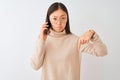 Young chinese woman talking on the smartphone over isolated white background Pointing down looking sad and upset, indicating Royalty Free Stock Photo