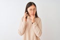 Young chinese woman talking on the smartphone over  white background Thinking worried about a question, concerned and Royalty Free Stock Photo