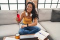 Young chinese woman using smartphone looking watch sitting on sofa at home Royalty Free Stock Photo