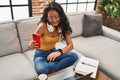 Young chinese woman using smartphone looking watch sitting on sofa at home Royalty Free Stock Photo