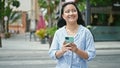 Young chinese woman using smartphone smiling at street Royalty Free Stock Photo